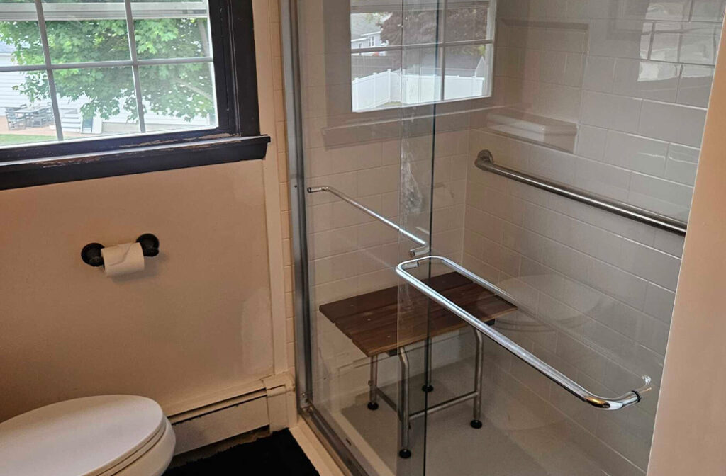 Tub-to-shower conversion in Cranston, RI featuring a low-threshold walk-in shower with professionally installed grab bars for improved accessibility and bathroom safety.